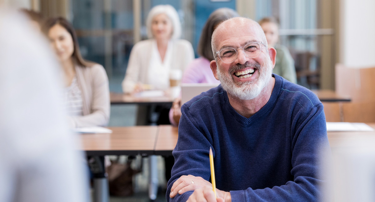Mature adult man laughs at unrecognizable teacher's joke