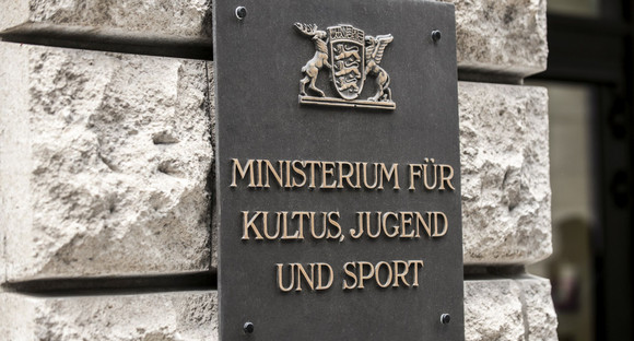 Das Wappen des Landes Baden-Württemberg auf einem Schild, darunter der Schriftzug "Ministerium für Kultus, Jugend und Sport" 