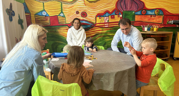 Staatssekretär Schebesta besucht im Rahemn des Direkteinstiegs Kita und sitzt dort mit Erzieherinnen und Kindern an einem kleinen Tisch