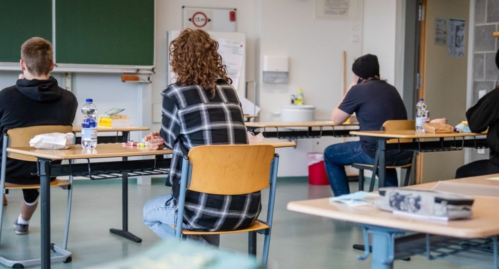 Prüflinge sitzen zur Prüfung an Einzeltischen in einem Klassenzimmer