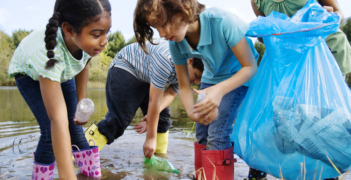 Kinder sammeln Müll in einem Teich