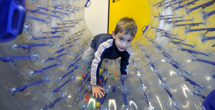 Ein Junge klettert durch eine Plastik-Röhre. 