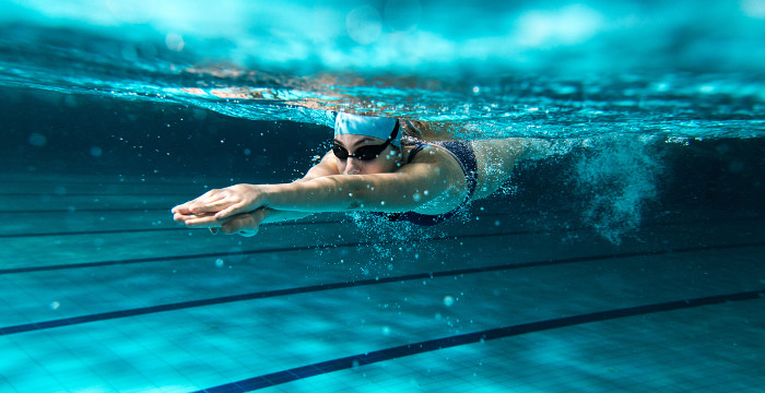 Eine Schwimmerin taucht ins Wasser ein.