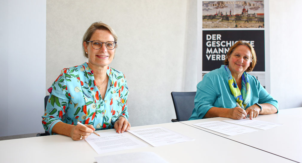 Kultusministerin Theresa Schopper und die Bildungsministerin in Rheinland-Pfalz, Dr. Stefanie Hubig, sitzen an einem Tisch und unterzeichnen die Kooperationsvereinbarung